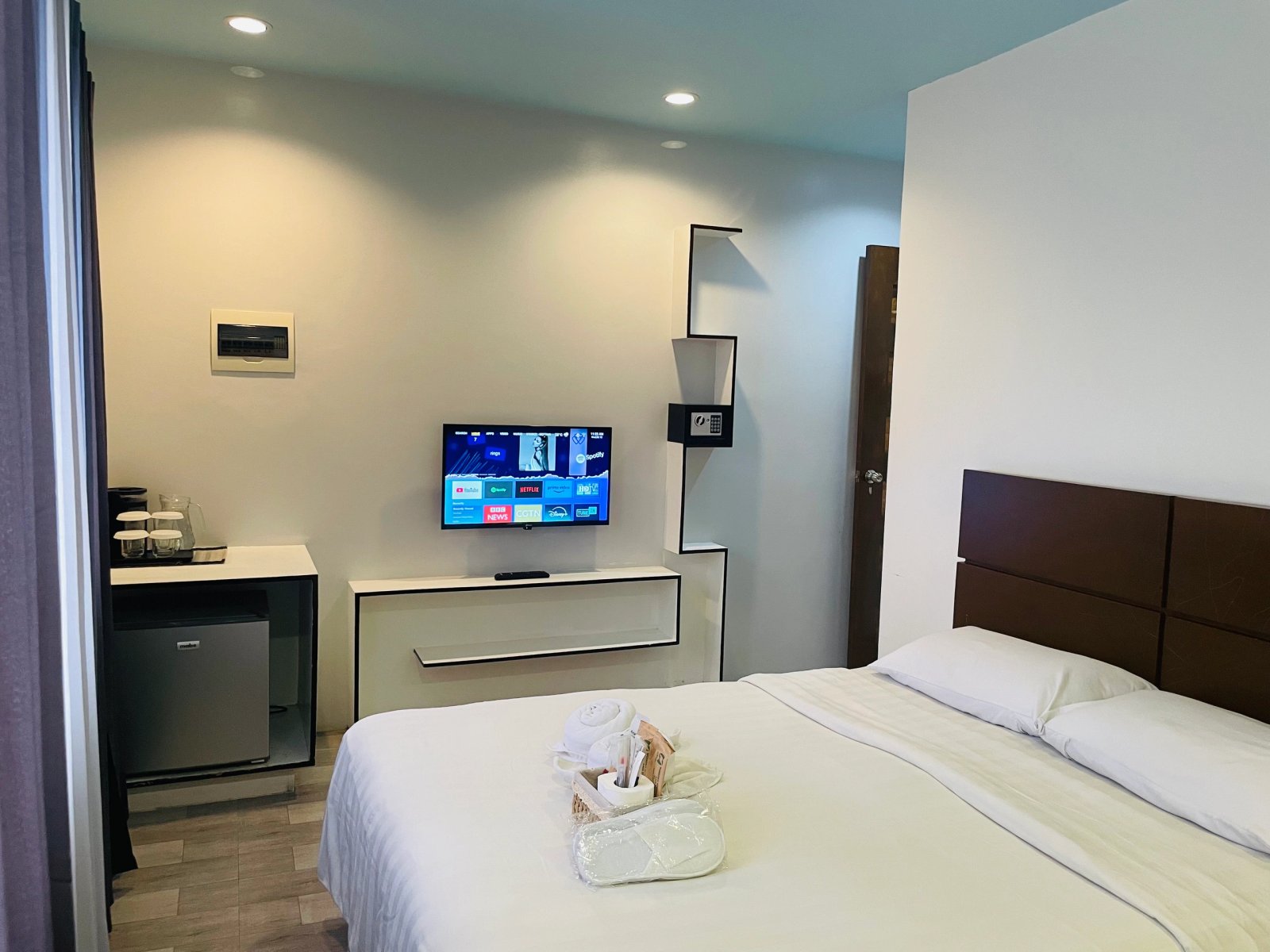 A cozy Kayong’s Inn room with a bed, television, and large curtained windows